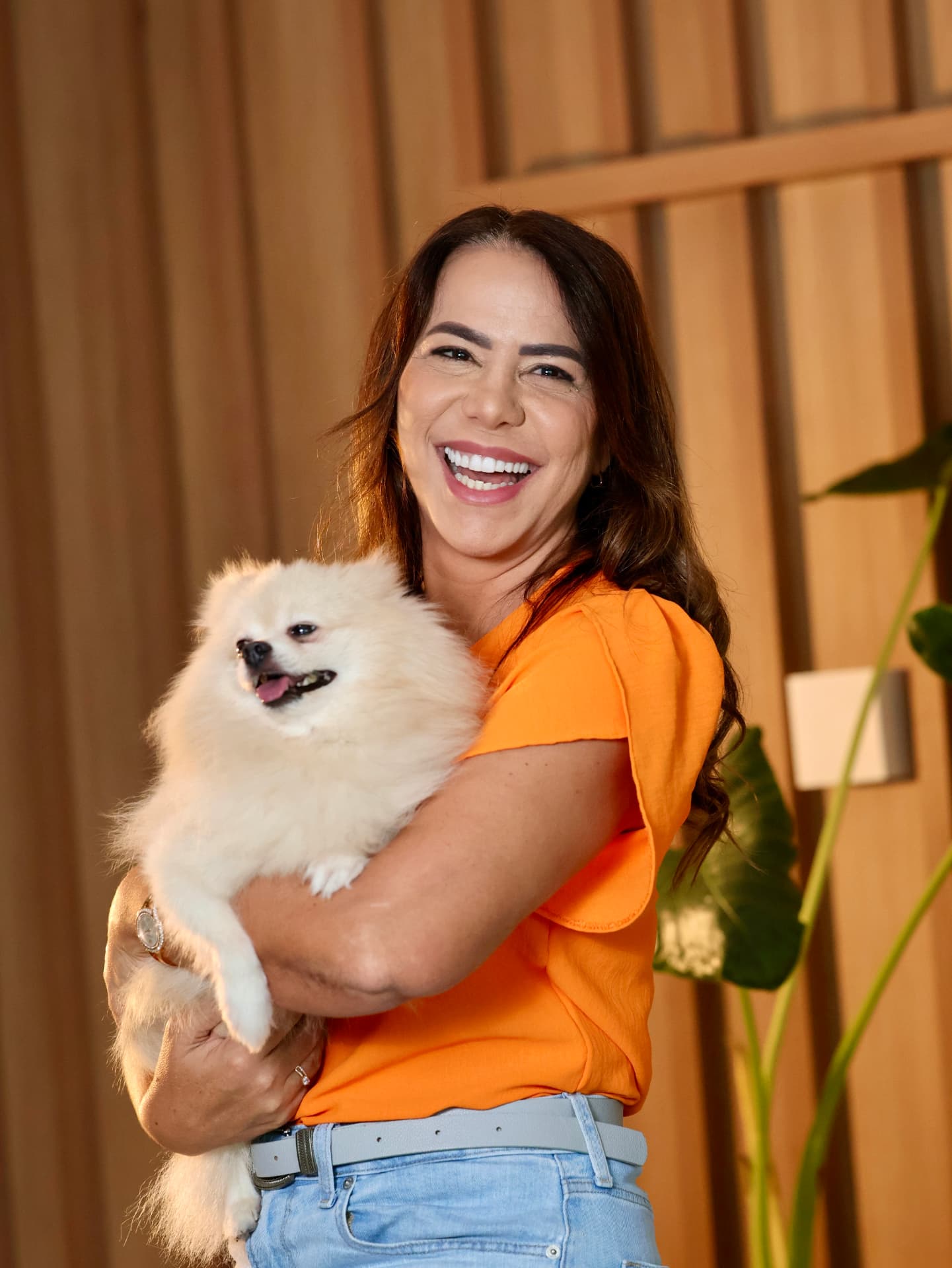 Débora Santana sorrindo com seu cachorro no colo